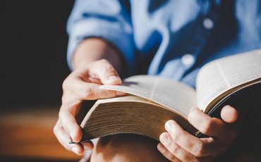 Spirituality and religion, Hands folded in prayer on a Holy Bible in church concept for faith.